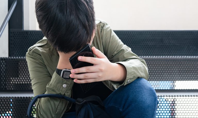 Ragazzo con cellulare in atteggiamento triste, che simboleggia le truffe online