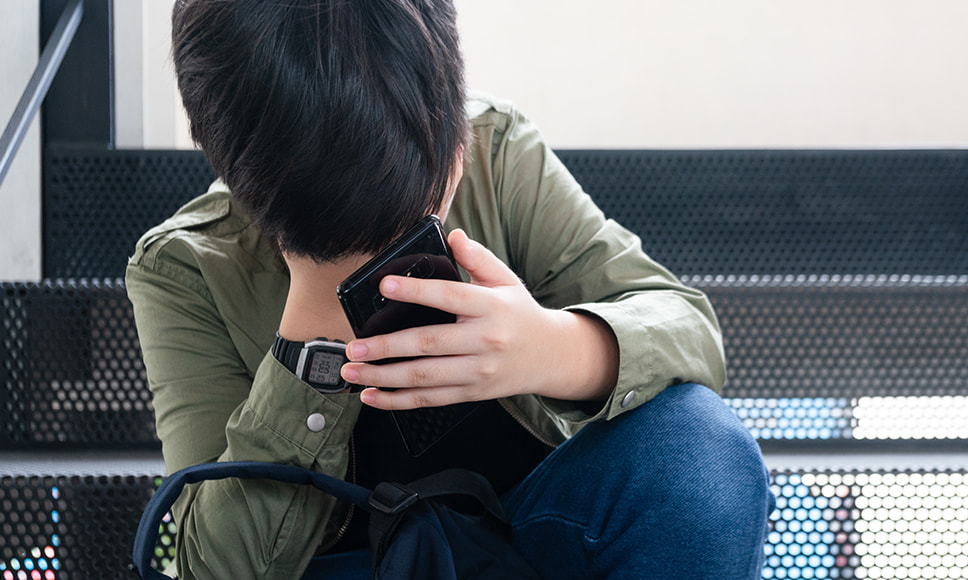 Ragazzo con cellulare in atteggiamento triste, che simboleggia le truffe online