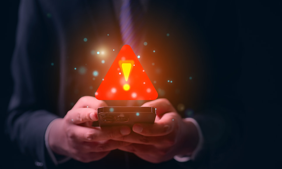 Mani che utilizzano smartphone e segnale di pericolo