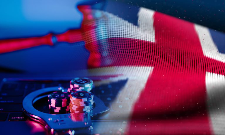 Bandiera inglese con fiches di casinò, manette e tastiera di un computer.