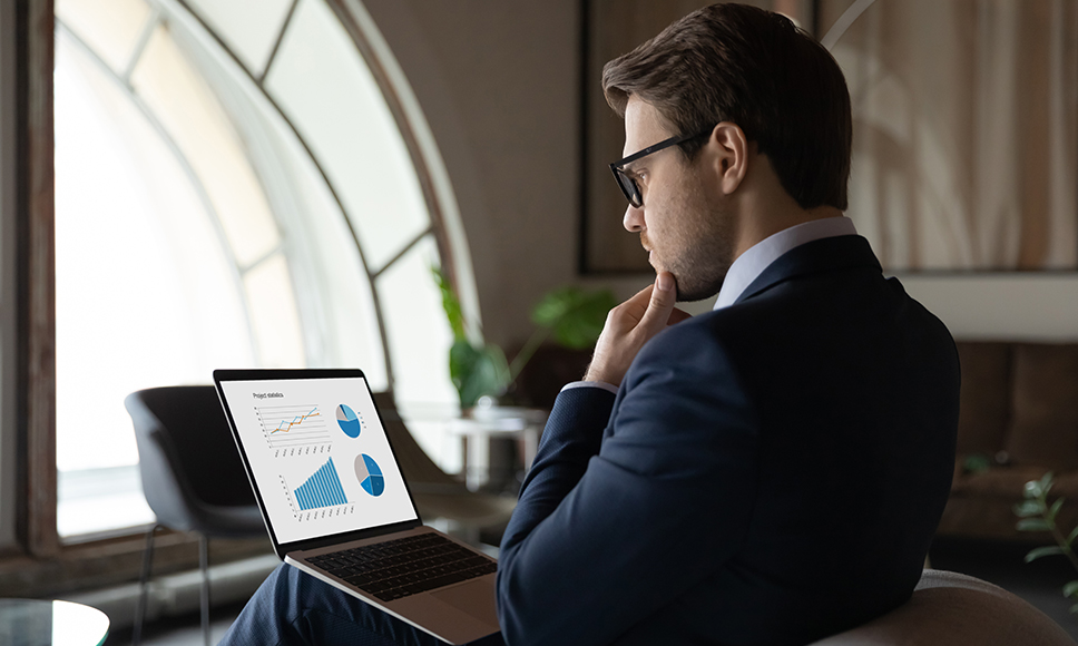 Uomo d’affari che consulta un laptop con grafici.