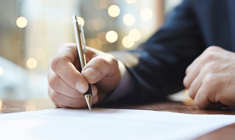Persona che redige un documento, a simboleggiare la truffa della falsa eredità.