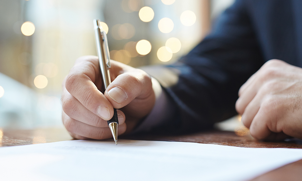 Persona che redige un documento, a simboleggiare la truffa della falsa eredità.