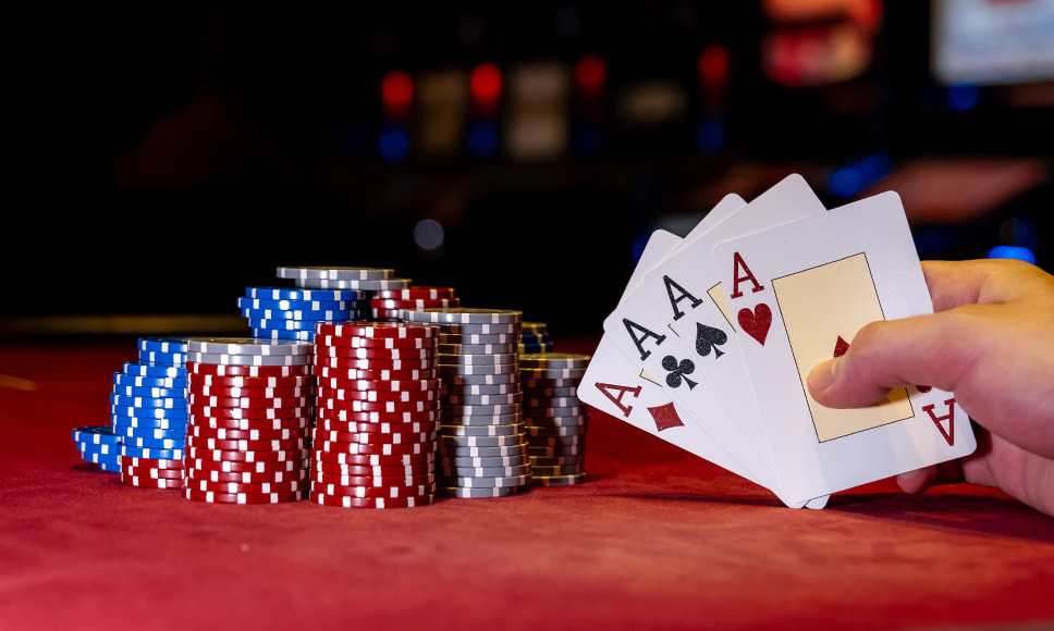 Fiches da casinò e mano che tiene un poker d’assi. 